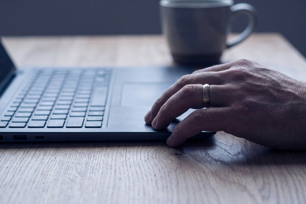 Hand ruht neben einer Laptop-Tastatur, während diktiert statt getippt wird